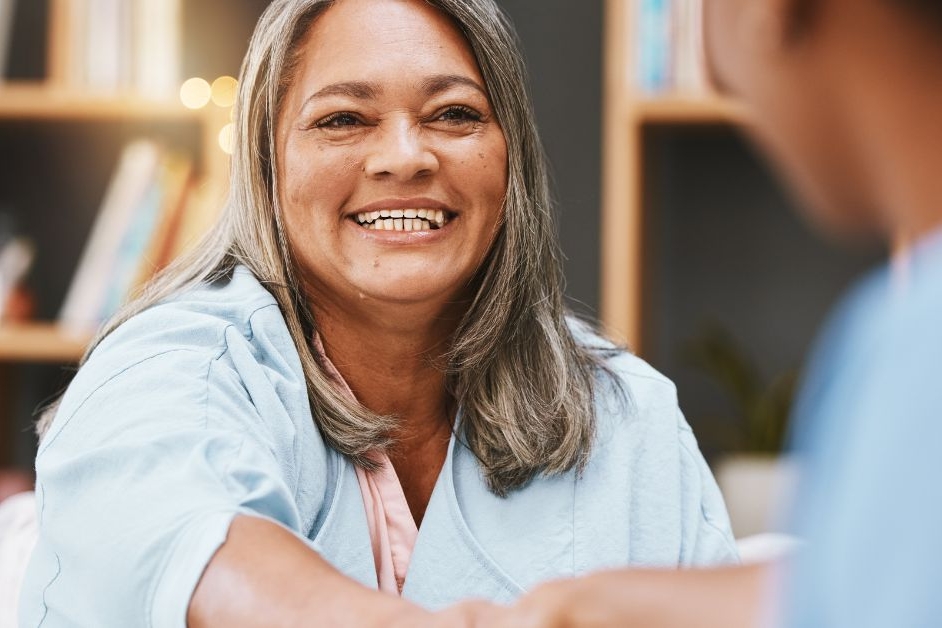 a smiling continuing healthcare funded patient shaking hands with another person in front
