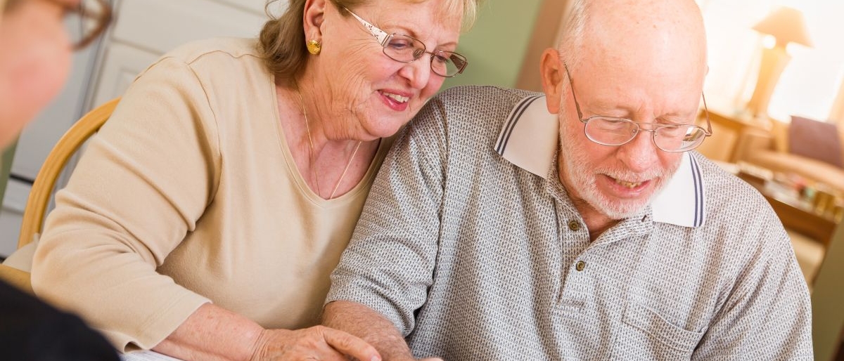 Elderly couple sat a table completing CHC review with assessor.