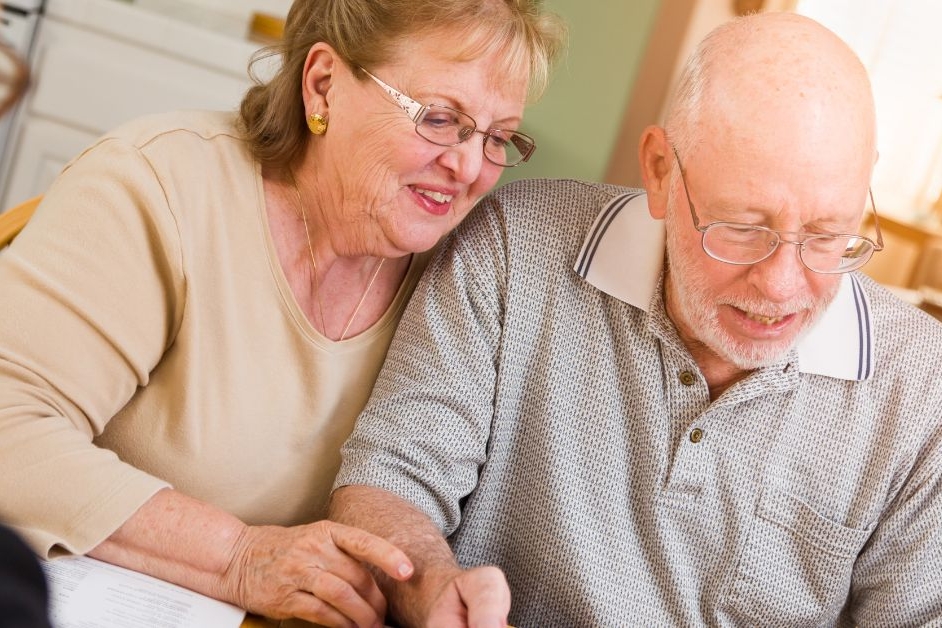 Elderly couple sat a table completing CHC review with assessor.