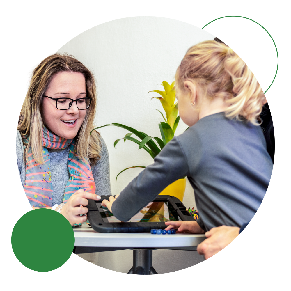 Child interacting with a tablet during a continuing care consultation with a healthcare professional and family member.