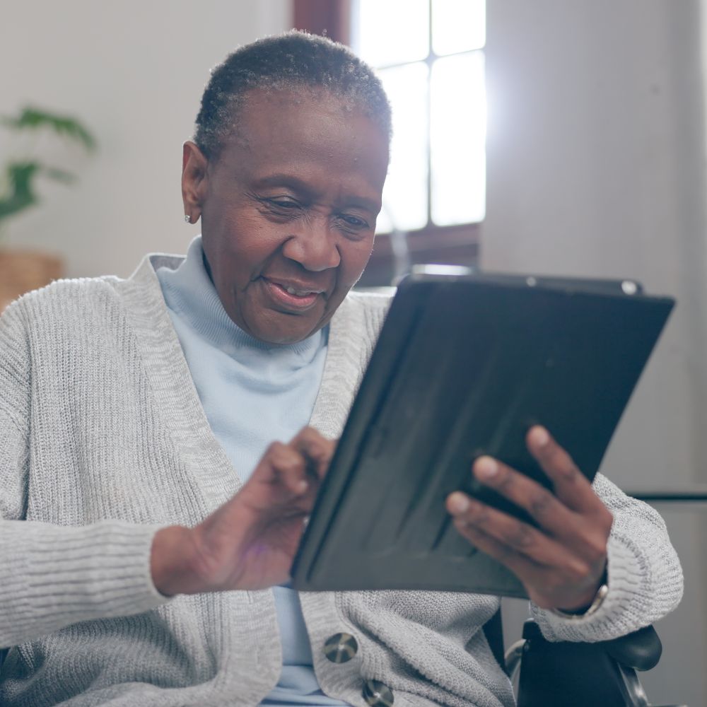 Woman in a wheelchair using a tablet to connect with Liaison Care team