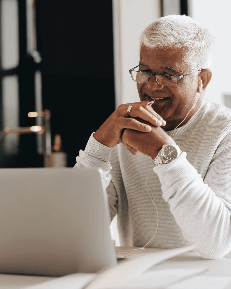 A male CHC social worker sat at a desk using his laptop to carry out remote reviews.
