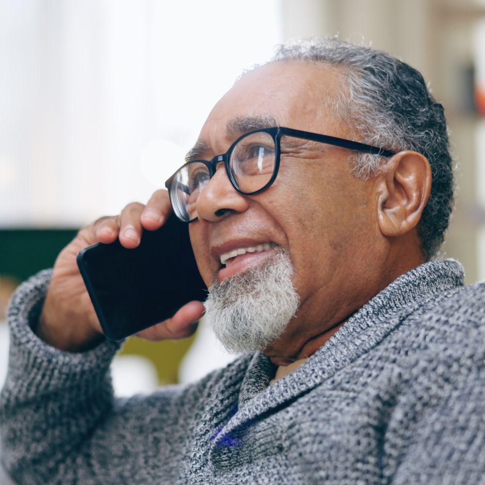 An elderly man holding a phone to his ear, speaking with the liaison care support team